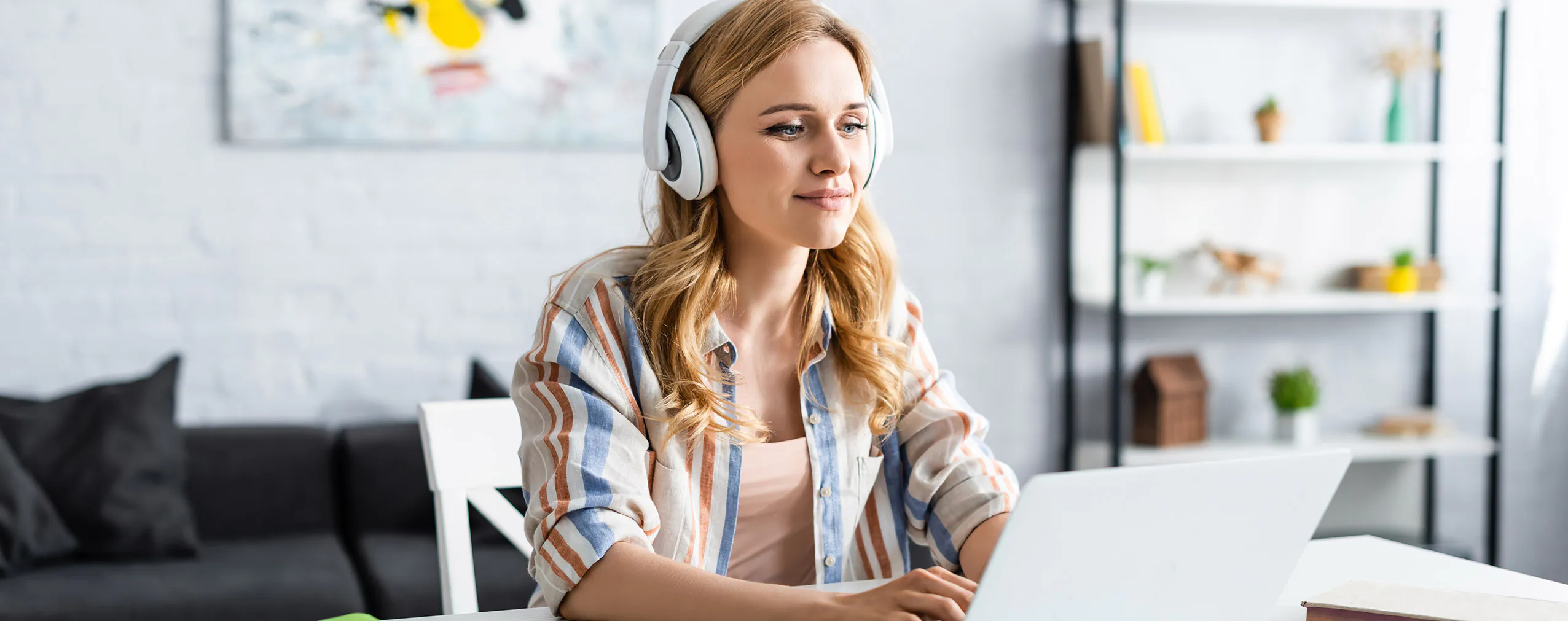 Kobieta w słuchawkach uczy się online na laptopie – e-learning